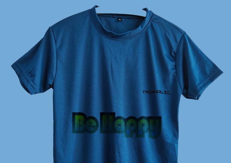 Person outdoors in matte blue t-shirt with “Be Happy” text effect design