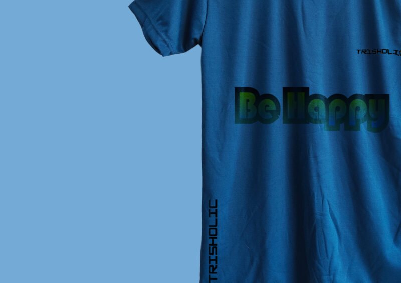 Stack of folded matte blue t-shirts with “Be Happy” printed on top