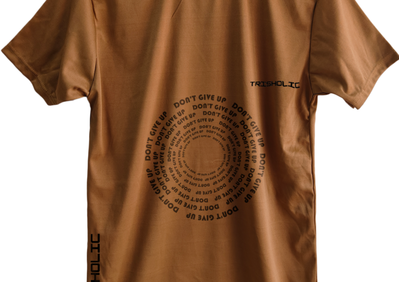 Black Trisholic t-shirt with bold white quote “Hustle Hard Stay Humble” across the chest.